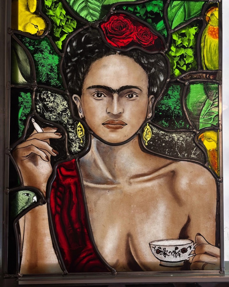 Stained glass portrait of Frida Kahlo with rose, parrots, and teacup
